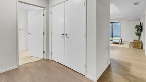 Een moderne kamer met een houten vloer, witte wanden en een grote garderobe met twee deuren.