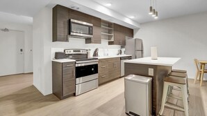 Een moderne keuken met roestvrijstalen apparatuur, houten keukenkastjes en een centraal kookeiland met krukken.