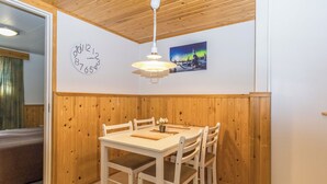 A dining area with a wooden table and chairs, a clock, and a picture on the wall.