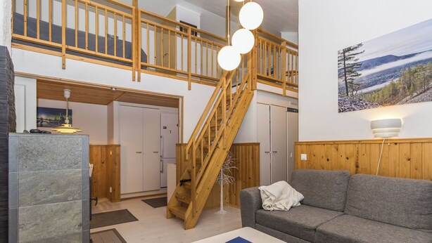 A spacious living area with a wooden staircase, a grey sofa, and a white coffee table.