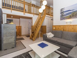 Een ruime woonkamer met een houten trap, een grijze bank en een witte salontafel.