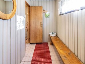 Ein Badezimmer mit Holzwänden, einer Holzbank, einer roten Matte, einem Waschbecken und einem Spiegel.