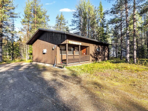 Eine Holzhütte mit Veranda, umgeben von hohen Bäumen.
