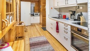 Een compacte keuken met houten kastjes, een magnetron, een koffiezetapparaat en een spoelbak.
