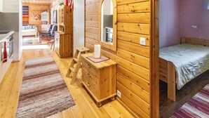 Een gezellig houten kamer in chaletstijl, met een bed, een dressoir en een spiegel.