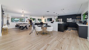 Una cocina moderna con una isla central, un comedor con una mesa redonda y sillas, y una sala de estar con un sofá y una mesa de centro.