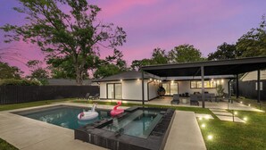Un jardín trasero con piscina, un porche cubierto y una casa.
