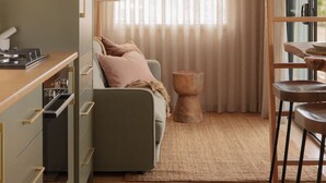 A compact kitchen with a dining area, a small seating space, and a window with sheer curtains.
