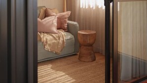 A room with a sliding glass door leading to a seating area with a sofa and a lamp.