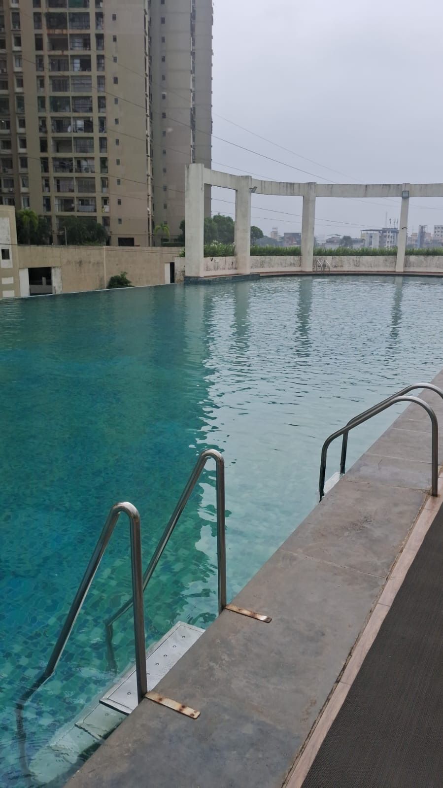 Ein Schwimmbecken mit Betonumrandung und Metallhandläufen.
