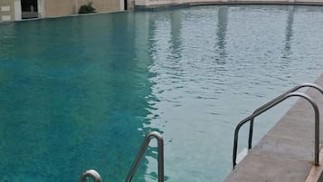 Ein Schwimmbecken mit Betonumrandung und Metallhandläufen.