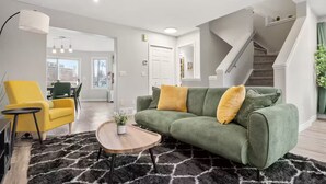 Una sala de estar moderna con un sofá verde, un sillón amarillo y una mesa de centro redonda.