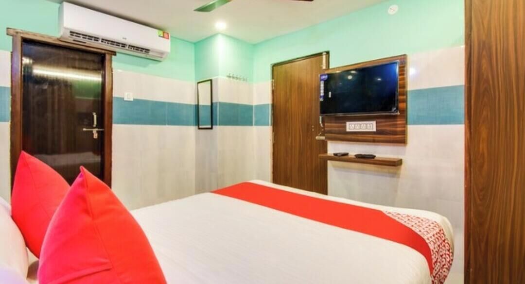 Una habitación de hotel con una cama, un televisor montado en la pared y un equipo de aire acondicionado.