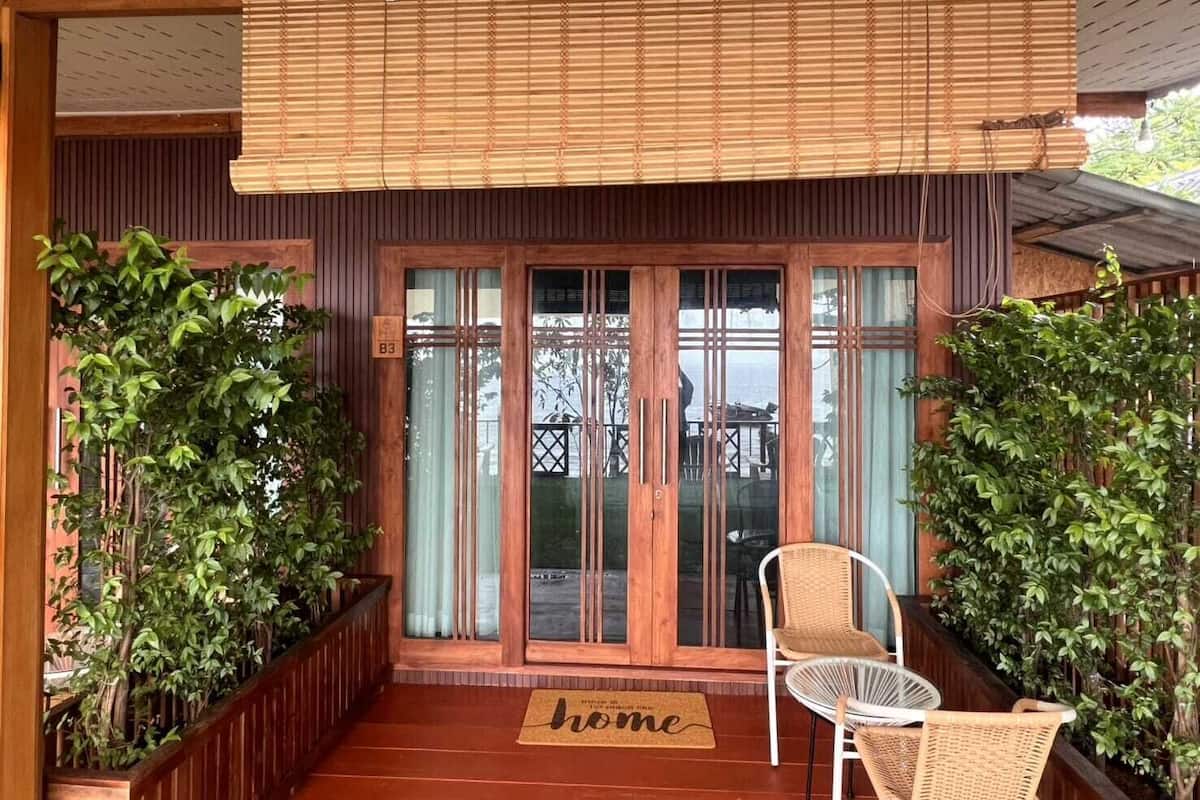 A wooden exterior with a sliding glass door, a wicker chair, and potted plants.