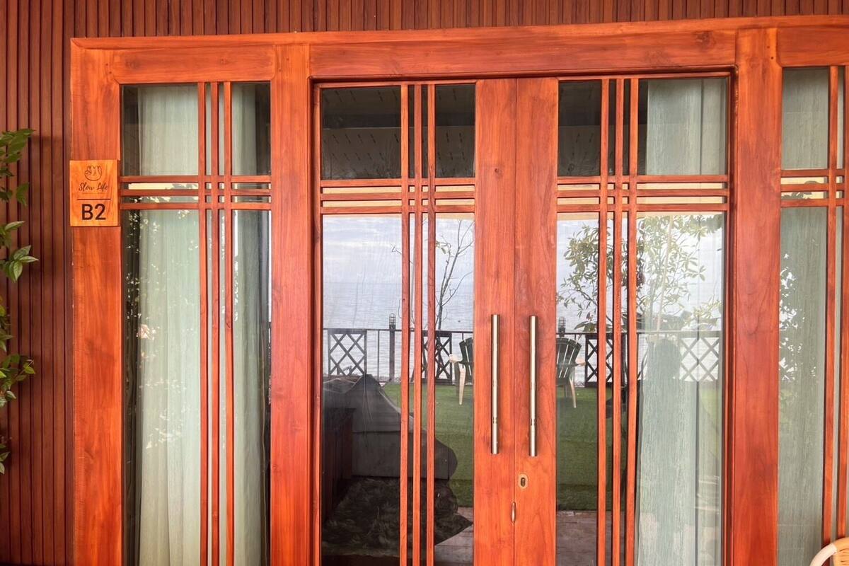 A wooden door with a sign reading "B2" and a view of an outdoor patio area with a grill and chairs.