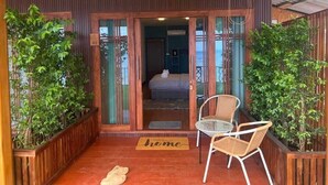 A wooden exterior with a balcony, a bed visible through the glass doors, and a 'home' mat on the floor. - Ban Slow Life Homestay Koh Libong (Ko Libong)