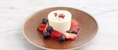 A dessert on a plate with strawberries and blueberries.