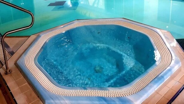 Ein Whirlpool in einem klaren Pool mit gefliestem Boden.