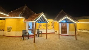 A courtyard with traditional buildings, each with a tiled roof and a door. - Rann Sanji Stay (Bhuj)