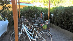 A covered bike parking area with multiple bicycles and a car parked nearby. - Appartamenti Granseola - Granseola -  Bilocale (Campo nell'Elba)