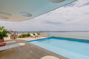 A swimming pool with a clear view of the sea, lounge chairs, and a pergola with plants. - Ocean Views & Private Jacuzzi Near Malecón del Mar (La Boquilla)