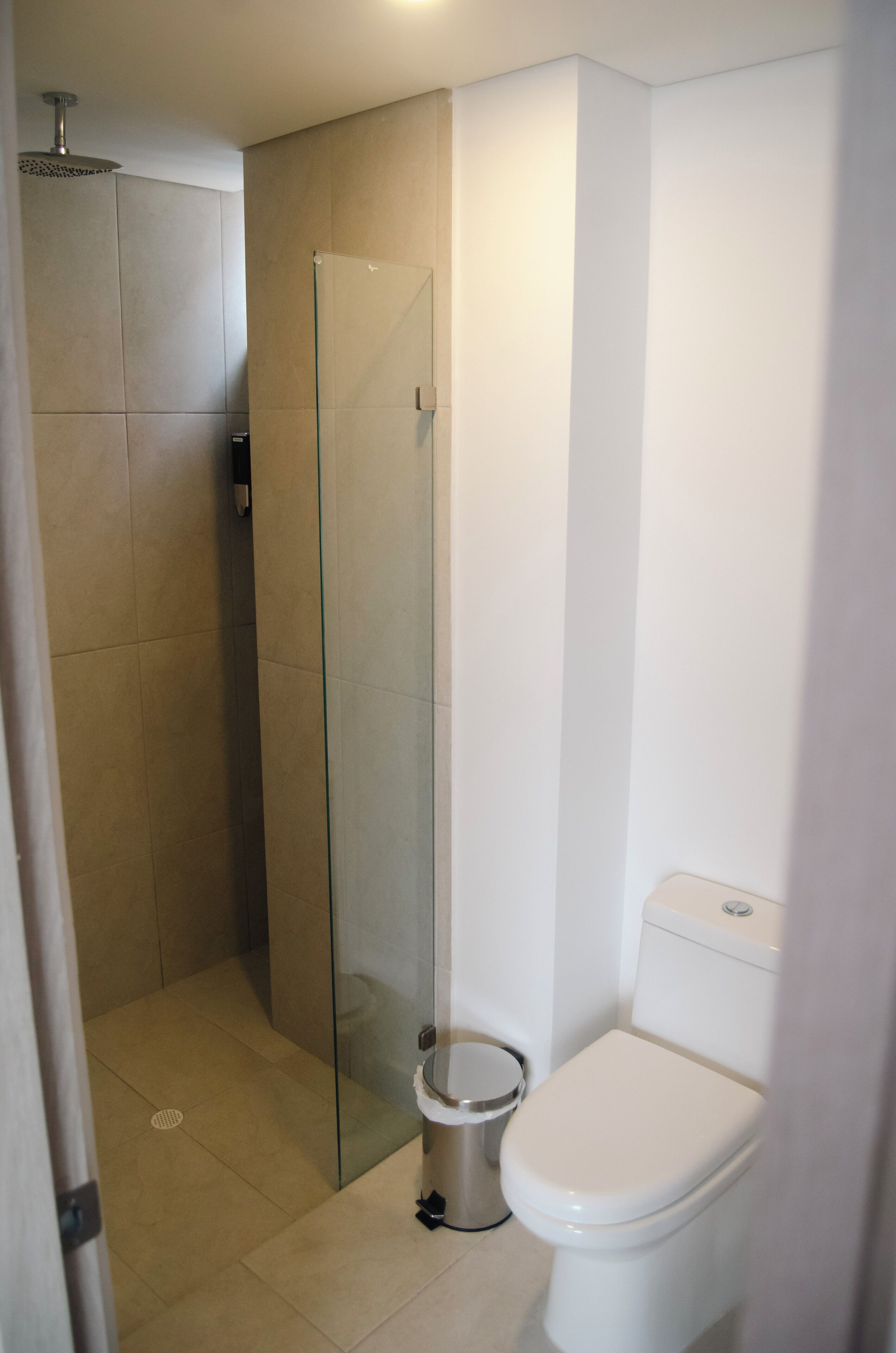 Ein Badezimmer mit einer Duschkabine, einer Toilette und einem Mülleimer.