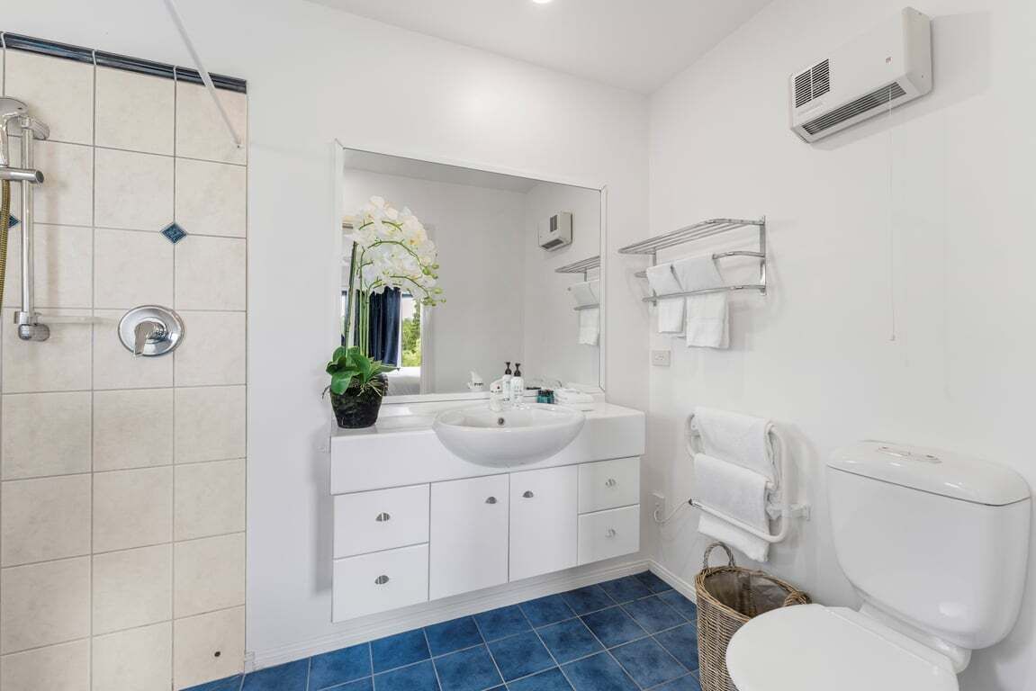 Ein modernes Badezimmer mit Waschbecken, Spiegel und Toilette in Weiß.
