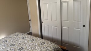 A bedroom with a bed, a wardrobe, and a door.