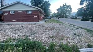 A single-story brick house with a sloped roof, a front porch, and a driveway leading to a street.