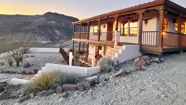 Un immeuble de deux étages doté d’un balcon, situé sur un site offrant une vue sur les montagnes.