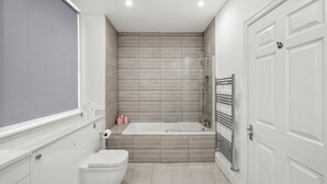 A modern bathroom with a toilet, sink, and bathtub. - Flat 1 Beauchamp Place (London)