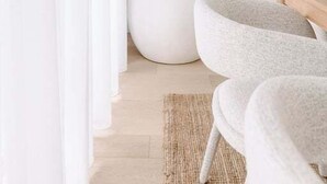 Quarto moderno com uma cadeira branca, uma planta grande em vaso e uma mesa de madeira.