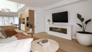 Uma sala de estar moderna com lareira, televisão de tela plana e uma grande planta em vaso.