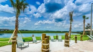 A poolside area with lounge chairs and wooden posts tied with ropes, overlooking a body of water. - Themed 5Bd Home, Movie and Game Room (4726) (Kissimmee)