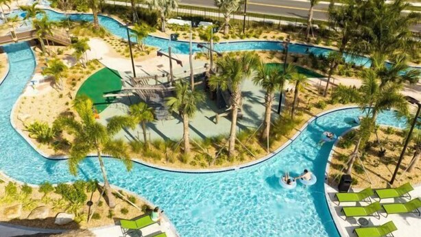 A large, multi-lane swimming pool with palm trees and lounge chairs. - Themed 5Bd Home, Movie and Game Room (4726) (Kissimmee)