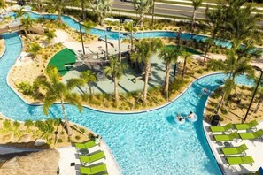 A large, multi-lane swimming pool with palm trees and lounge chairs. - Themed 5Bd Home, Movie and Game Room (4726) (Kissimmee)