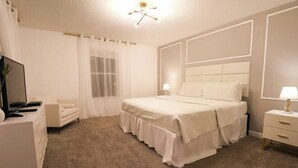 A bedroom with a bed, a dresser, a TV, and a window with curtains. - Themed 5Bd Home, Movie and Game Room (4726) (Kissimmee)