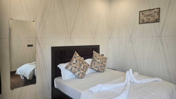 Ein Hotelzimmer mit einem großen Bett, einem Spiegel und einem gerahmten Bild an der Wand.