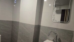 Ein Badezimmer mit einem weißen Waschbecken, einem Spiegel mit floralem Dekor und einer Duschkabine.