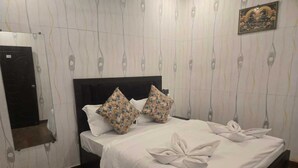 Ein ordentlich bezogenes Bett mit floralen Kissen, einem dunklen Kopfteil und einer dekorativen Wandleiste.