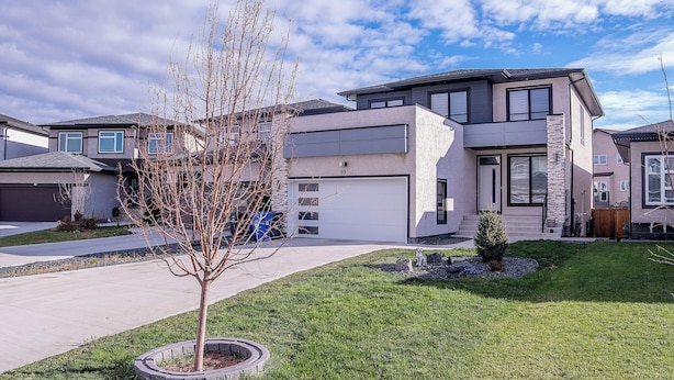 A modern two-story house with a garage, a well-maintained lawn, and a small tree in the front yard.