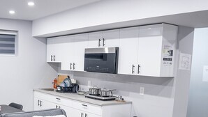 A compact kitchen with white cabinets, a built-in microwave, and a refrigerator.