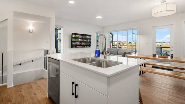 A modern kitchen with white cabinetry, a stainless steel sink, and a large window offering a view of the outside. - Luxury Family Retreat w/ Games, King Bed & Garage (Edmonton)