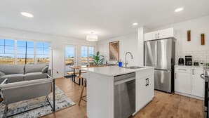 A modern kitchen with a central island, stainless steel appliances, and a view to the outside. - Luxury Family Retreat w/ Games, King Bed & Garage (Edmonton)