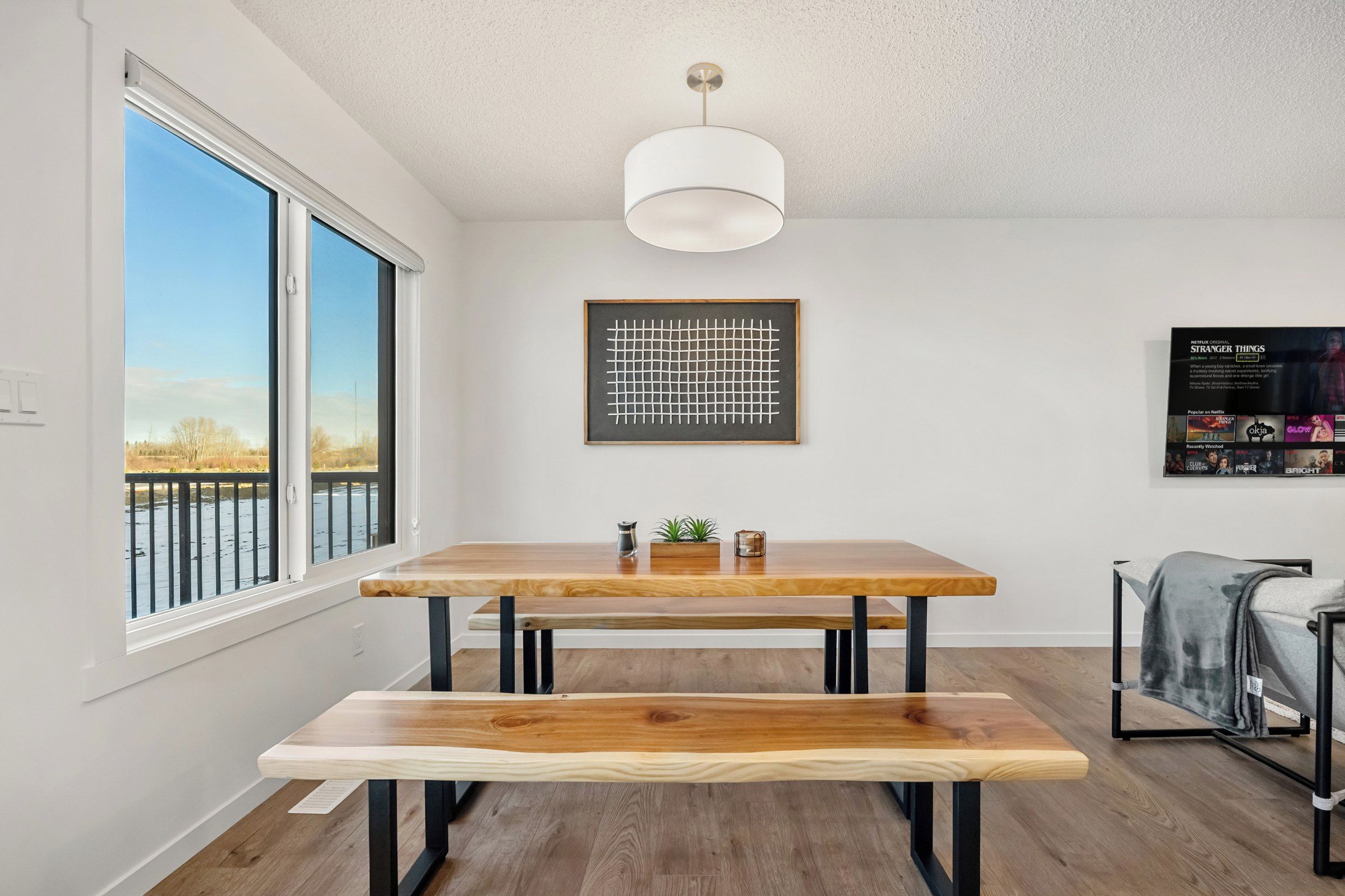 Un interior moderno con una mesa de comedor de madera, un banco y una lámpara de techo.