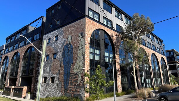 En moderne bygning med store vinduer, en murstensfacade og et muralmaleri.