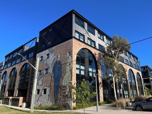 Een modern gebouw met grote ramen, een gevel van baksteen en een muurschildering.