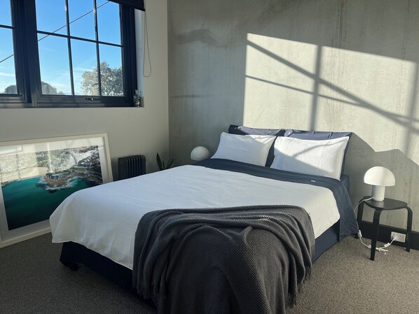 Una camera da letto con un letto, un quadro incorniciato, un termosifone, una lampada e una finestra vista mare.