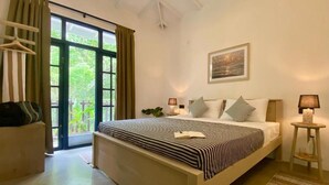 Un dormitorio con cama, mesitas de noche, una ventana con cortinas, un perchero y un cuadro en la pared.