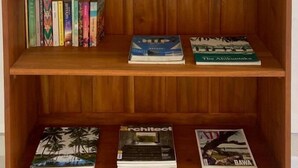 Una estantería de madera con tres repisas, cada una con libros y objetos decorativos.